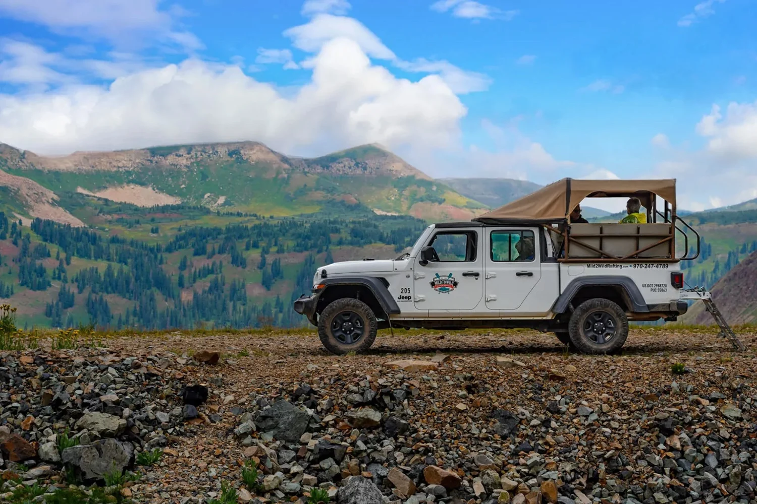 A Mild 2 Wild jeep is parked on a mountain road