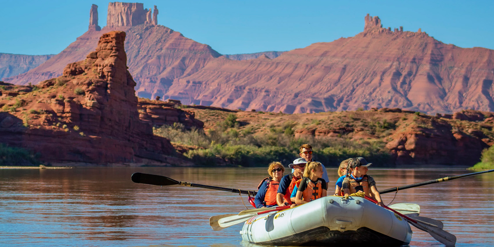 Wide shot of a raft on the castle Valley section of the Colroado River- Red rock - blue sky - Mild to Wild