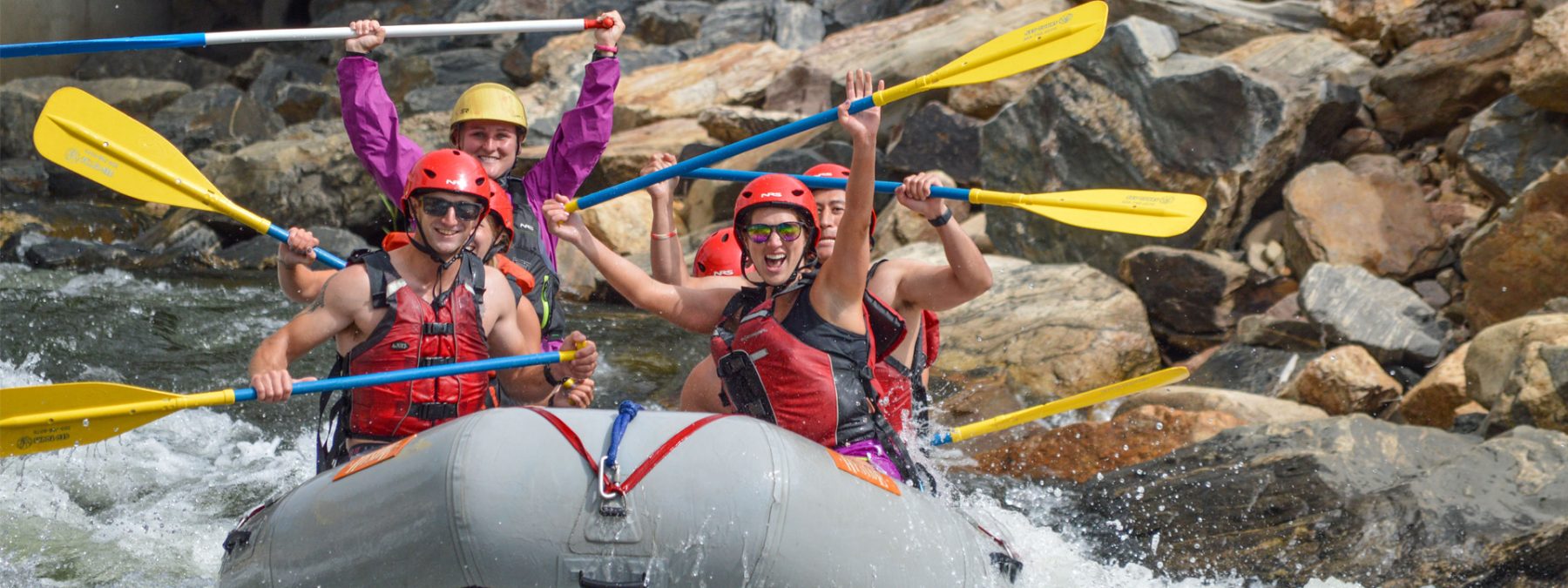 Guide and guests celebrating on raft with paddles in air going through whitewater - Clear Creek - Denver, Coloradogong