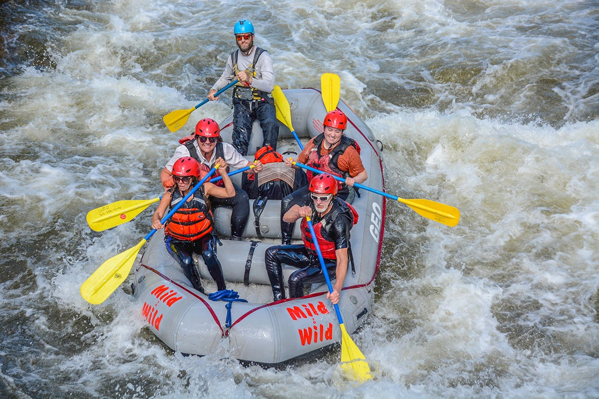 close up of group of rafters in red helmets paddling through white water rapids on Clear Creek near Idaho Springs, Colorado, with a Mild to Wild guide.