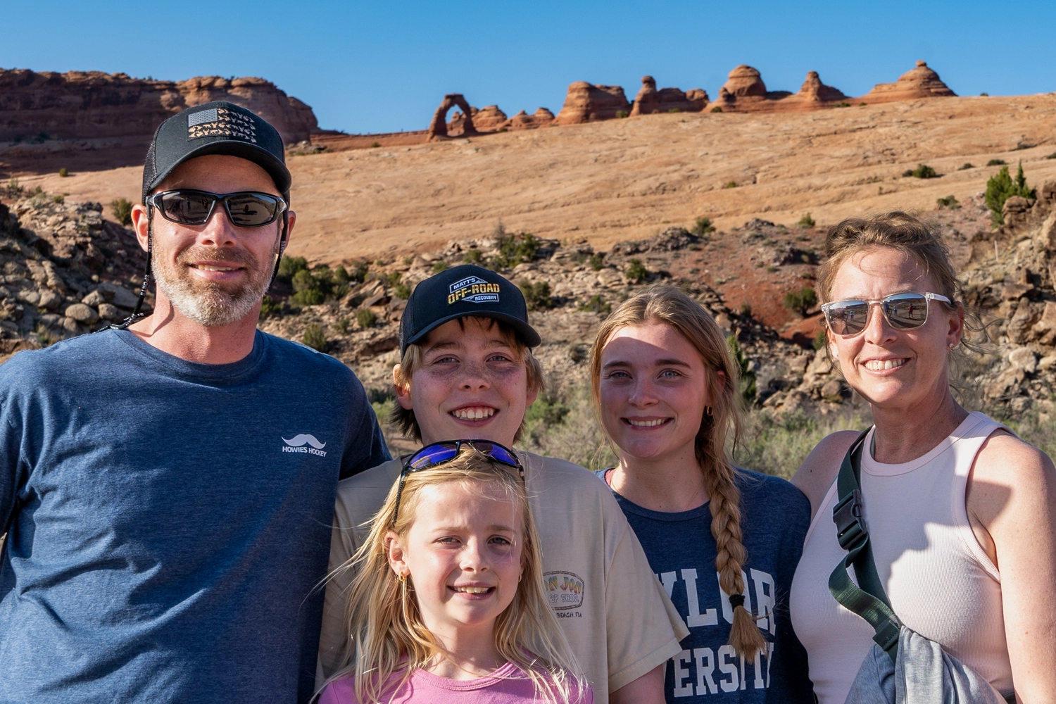 Family standing in front of Delicate Arch - Arches National Park, Moab, Utah