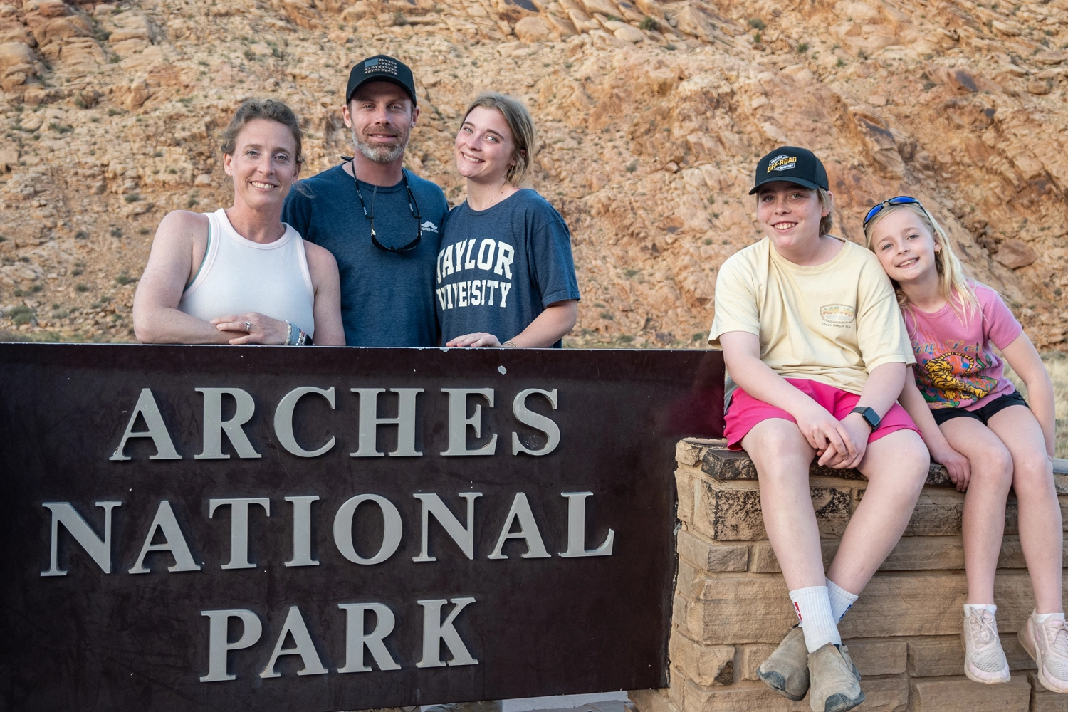 Family standing in front of the Arches National Park sign at Arches National Park - Moab, Utah