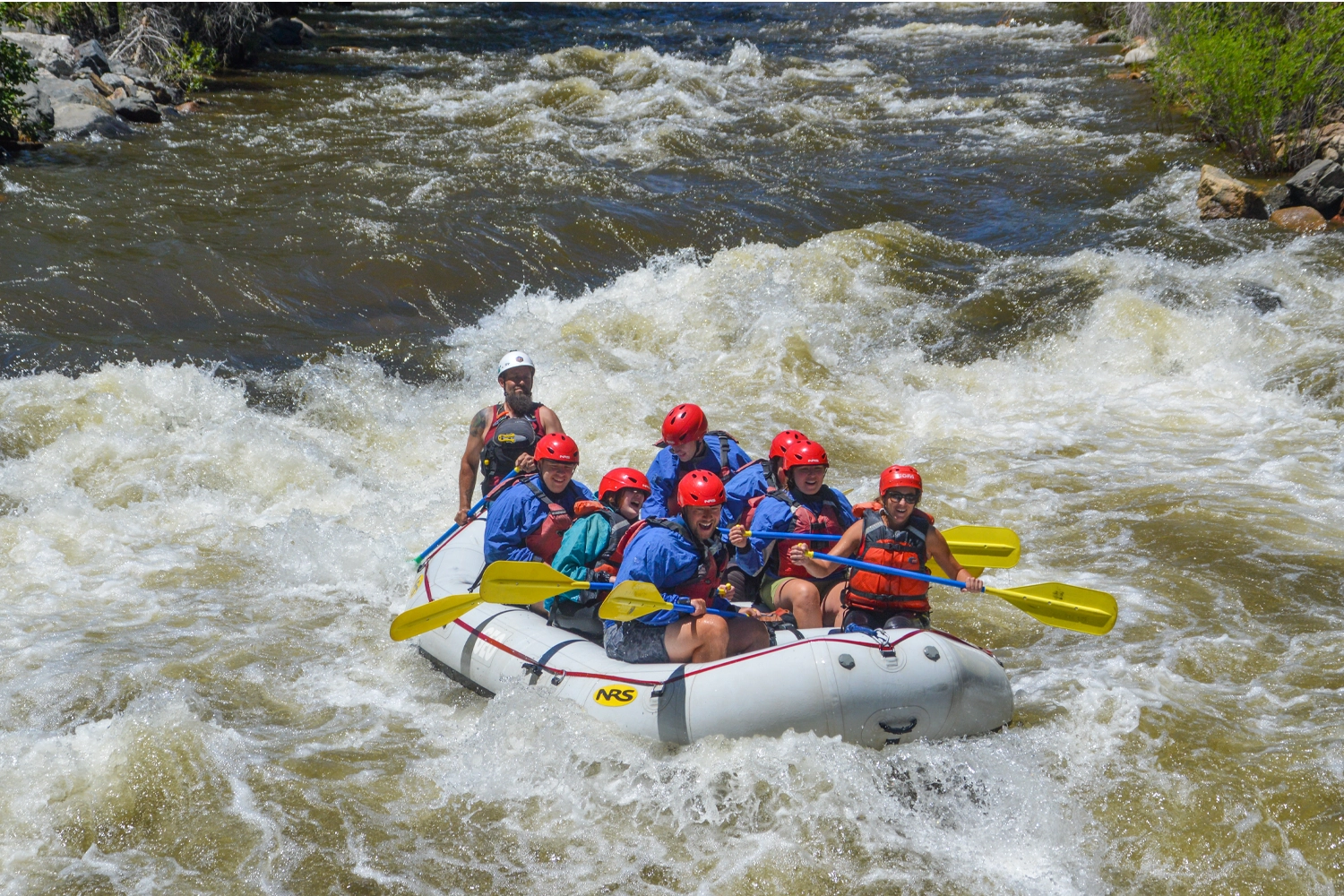 Raft full of smiling guests going through whitewater on Clear Creek in Idaho Springs, Colorado