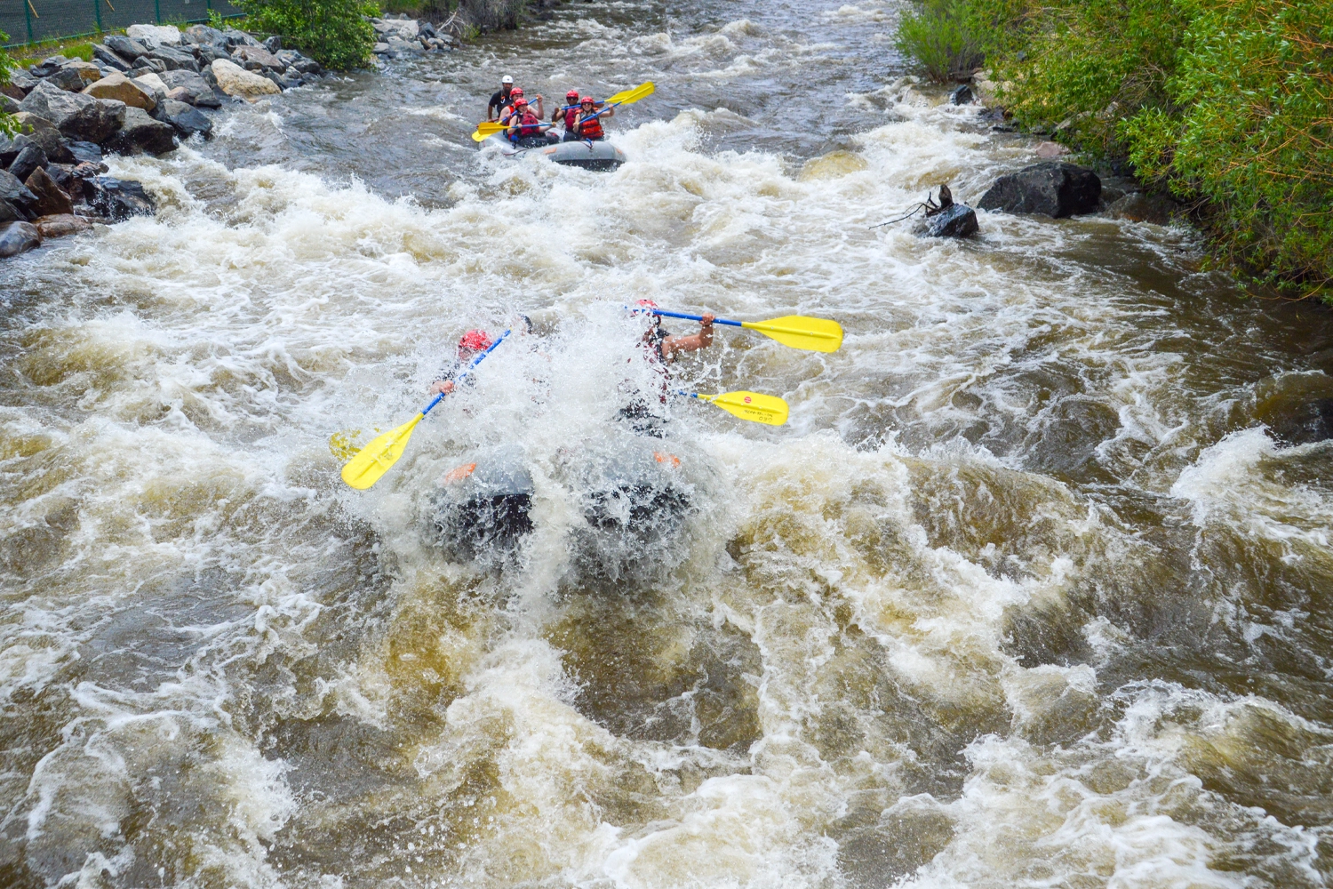 Rafts shrouded in whitewater paddling through rapids in Clear Creek - Idaho Springs, Colorado