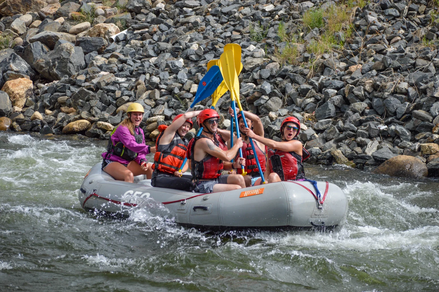 guests and guide on raft celebrating with paddles in air on Clear Creek - Denver, Colorado