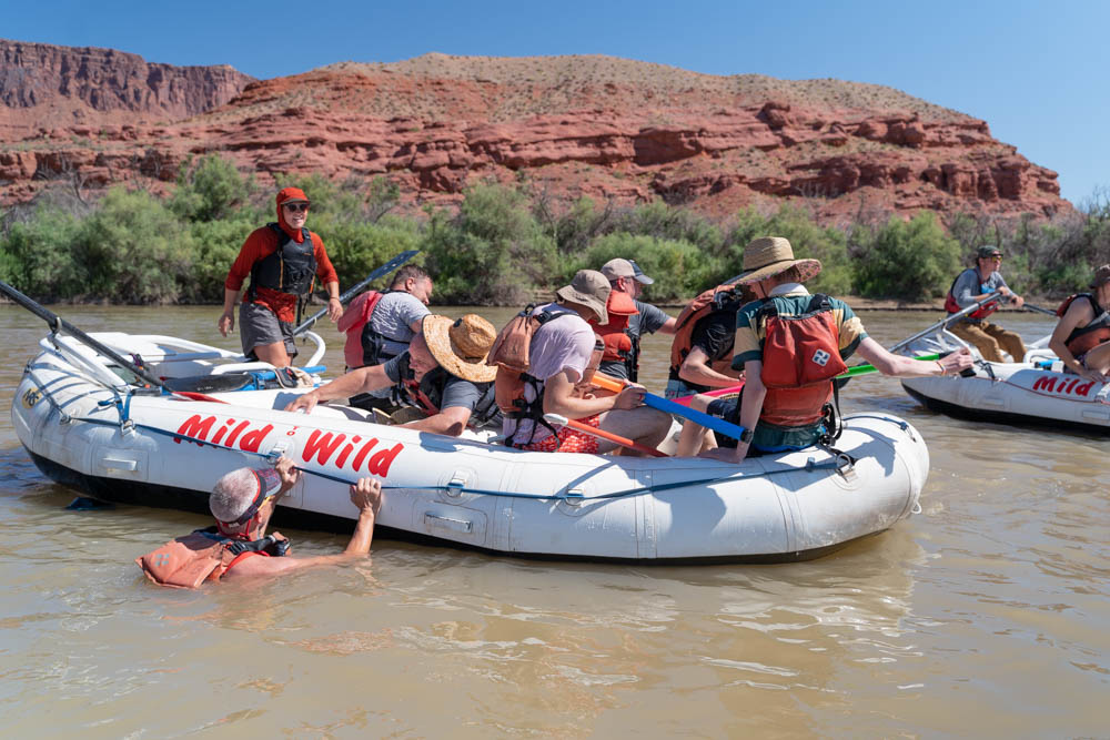 Raft in Castle Valley - Guest hanging off side of raft in the Colorado River