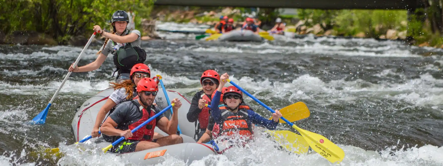 female guide rowing raft with guests through whitewater in Clear Creek - Denver, Colorado