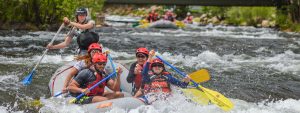 female guide rowing raft with guests through whitewater in Clear Creek - Denver, Colorado