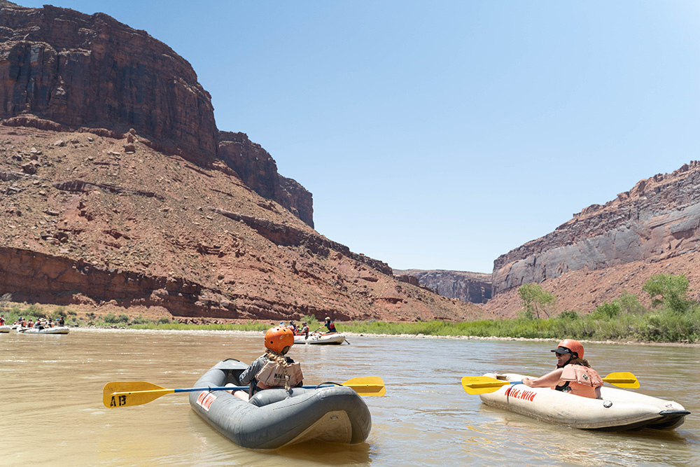 two inflatable kayakers in Castle Valley with red rock in background - Colorado River - Moab Utah - Mild to Wild