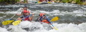 medium wide shot of raft paddling through whitewater rapids in clear creek - Idaho Springs Colorado near Denver