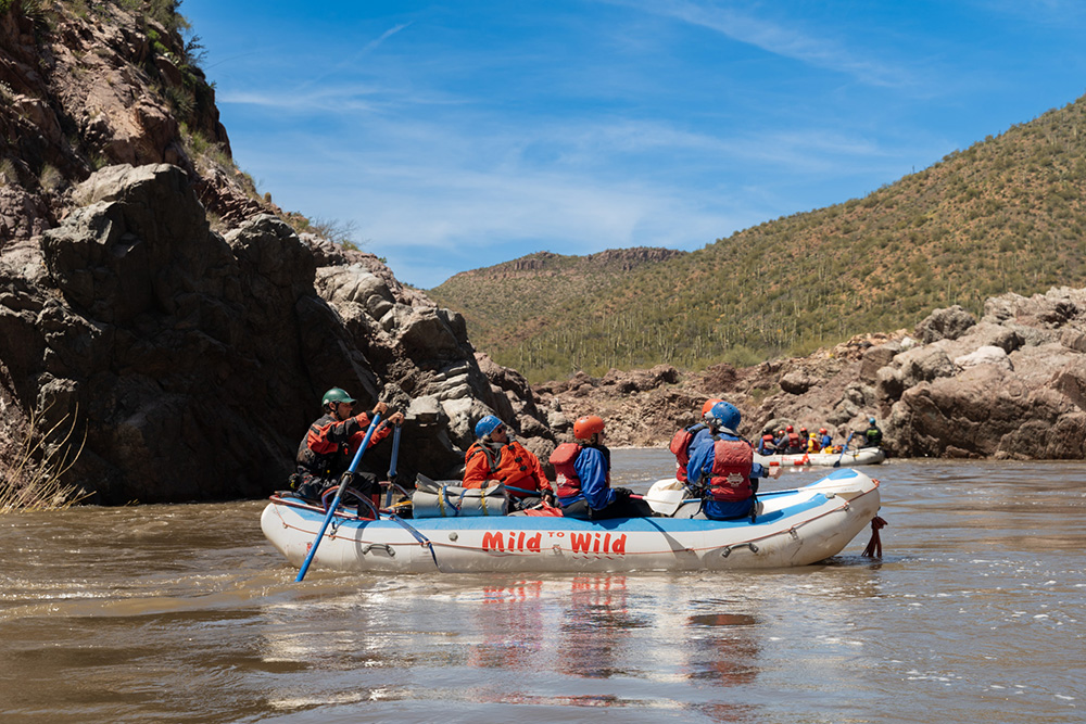 Medium shot of raft on the Salt River with desert landscape surroundings
