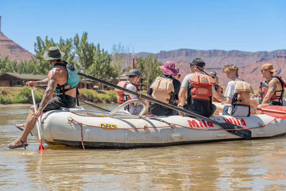 river guide sitting at the end of the raft on the colorado river with guests - Castle Valley - Moab Utah - Mild to Wild