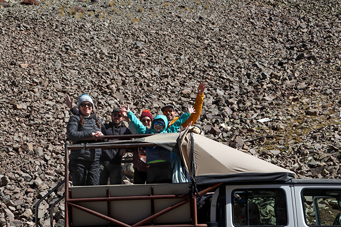 Famly standing up in the back of a jeep with a giant rock pile behind them