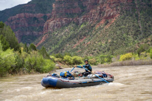 Wide shot of the Dolores River with a raft in the middle of river - Mild to Wild - Mountain backdrop