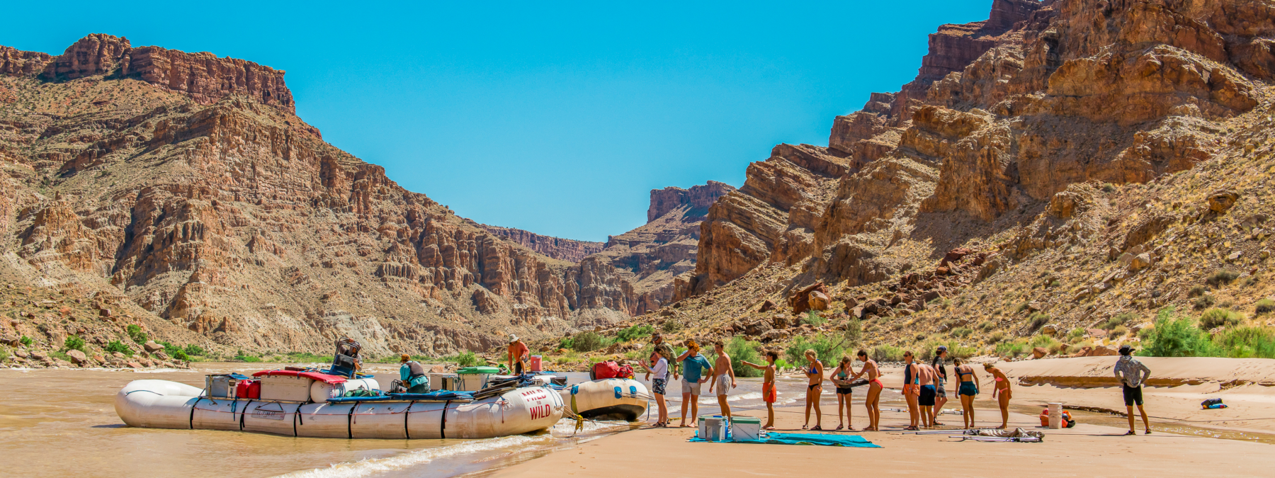 Wide shot of Cataract Canyon with people on shore - fire lining items from rafts - Mild to Wild