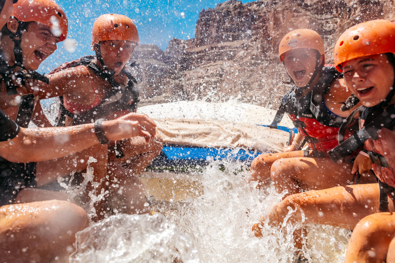 Shot from in the boat of kids getting splashed through a rapid in Cataract Canyon