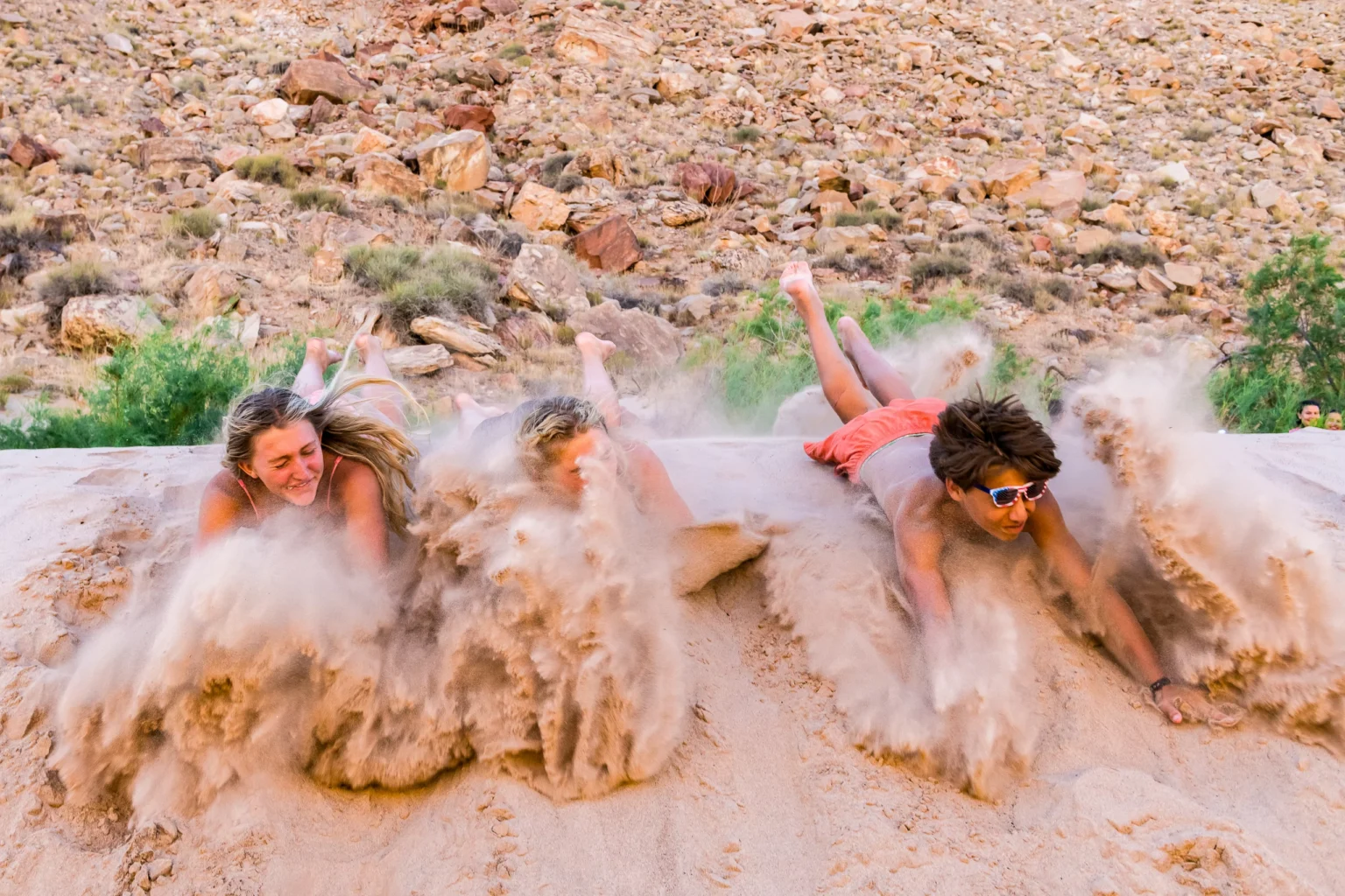 Kids jumping into the sand on the beach in Cataract Canyon