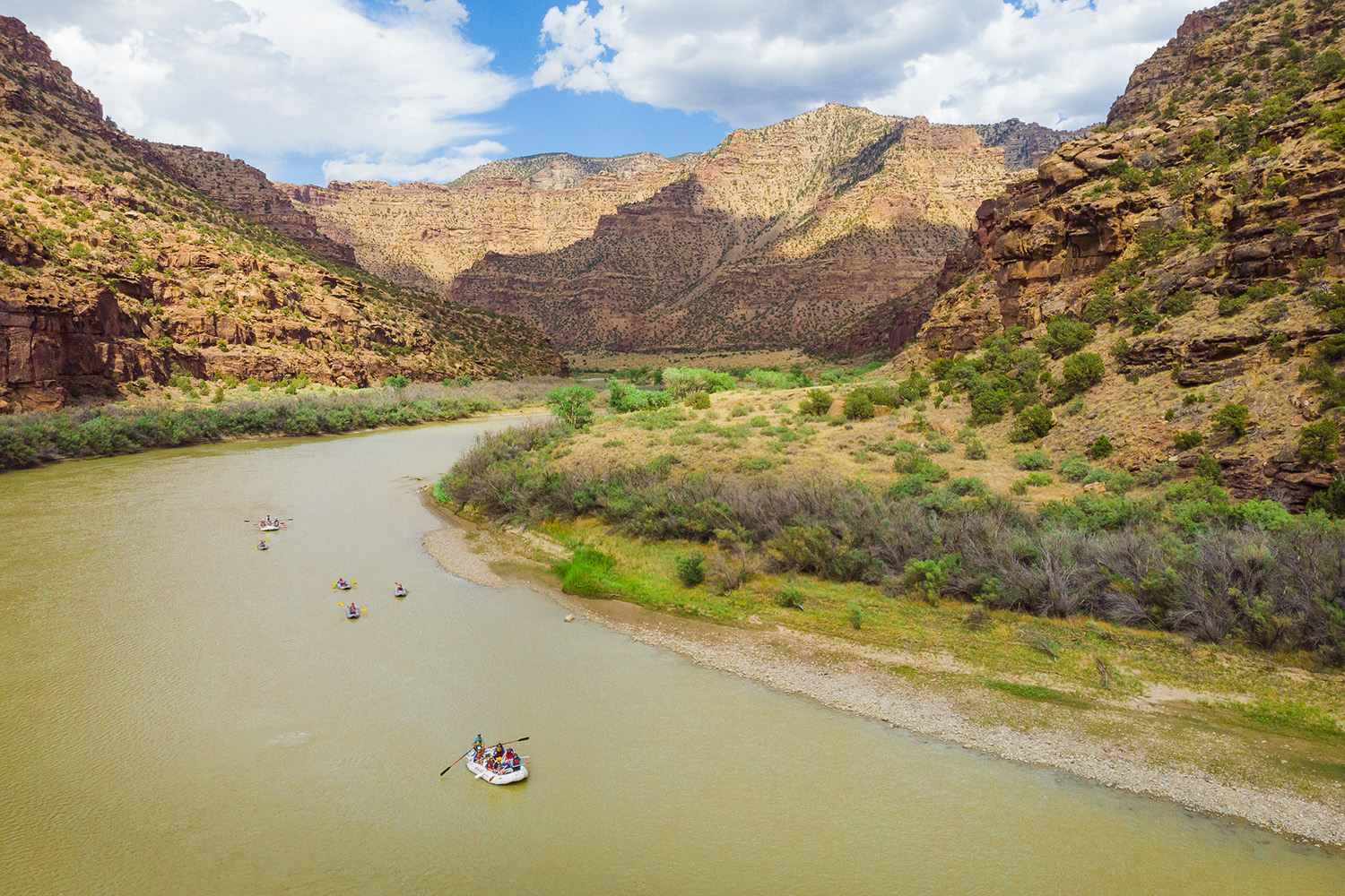 drone shot of desolation canyon with rafts in the middle of river - blue sky with some clouds - Mild to Wild