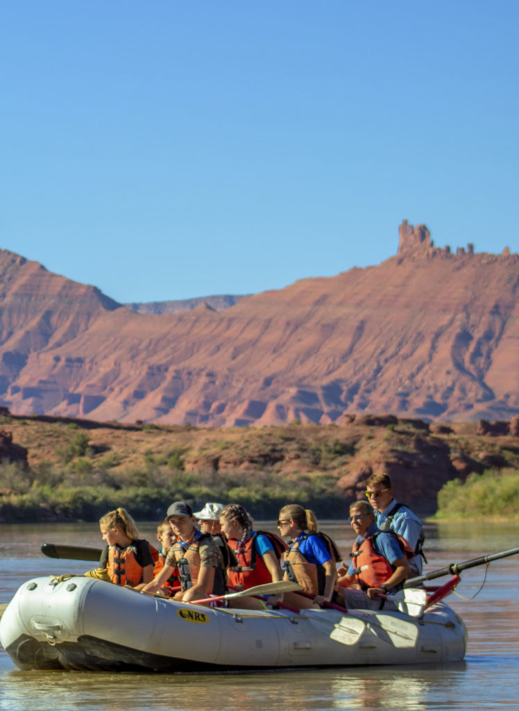 a raft on the Colorado river with rock formations in the background