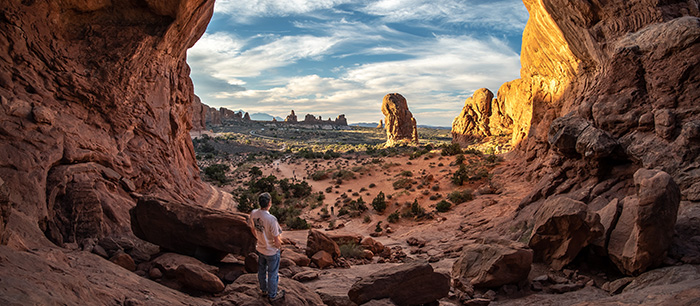 man looking out through an arch in Moab, Utah - Scenic shot