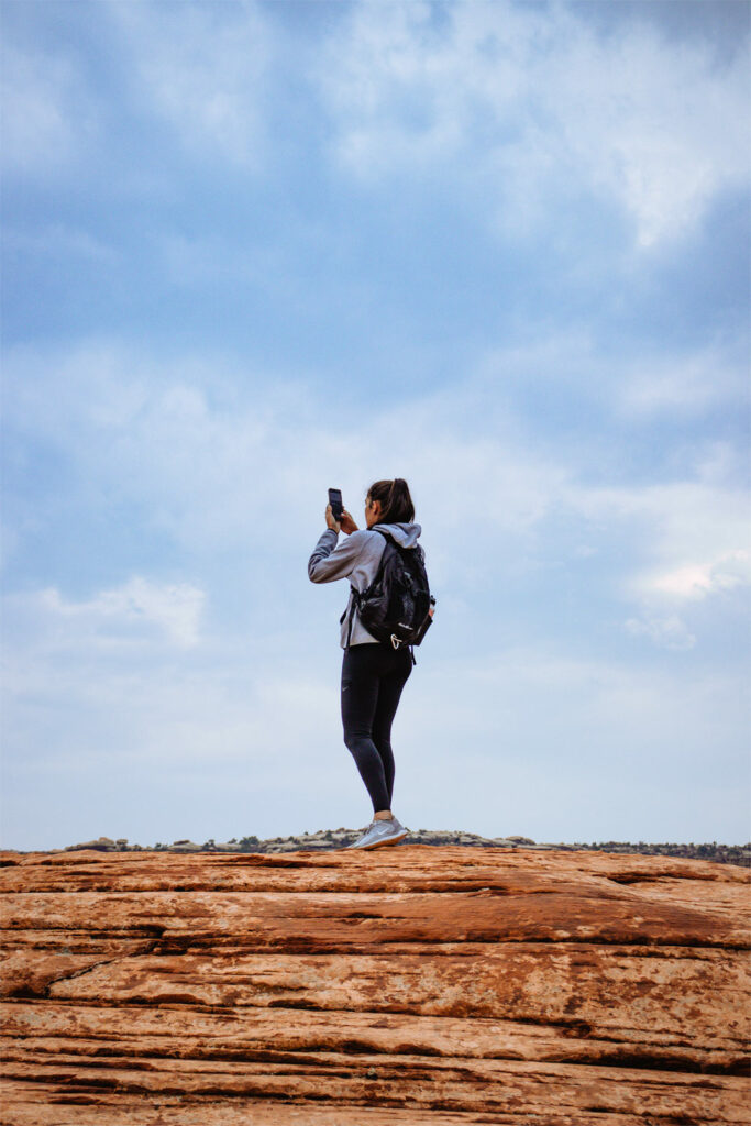 Woman Taking Photo Hiking At Gemini Bridges - Moab, Utah - Mild to Wild Rafting & Jeep Tours