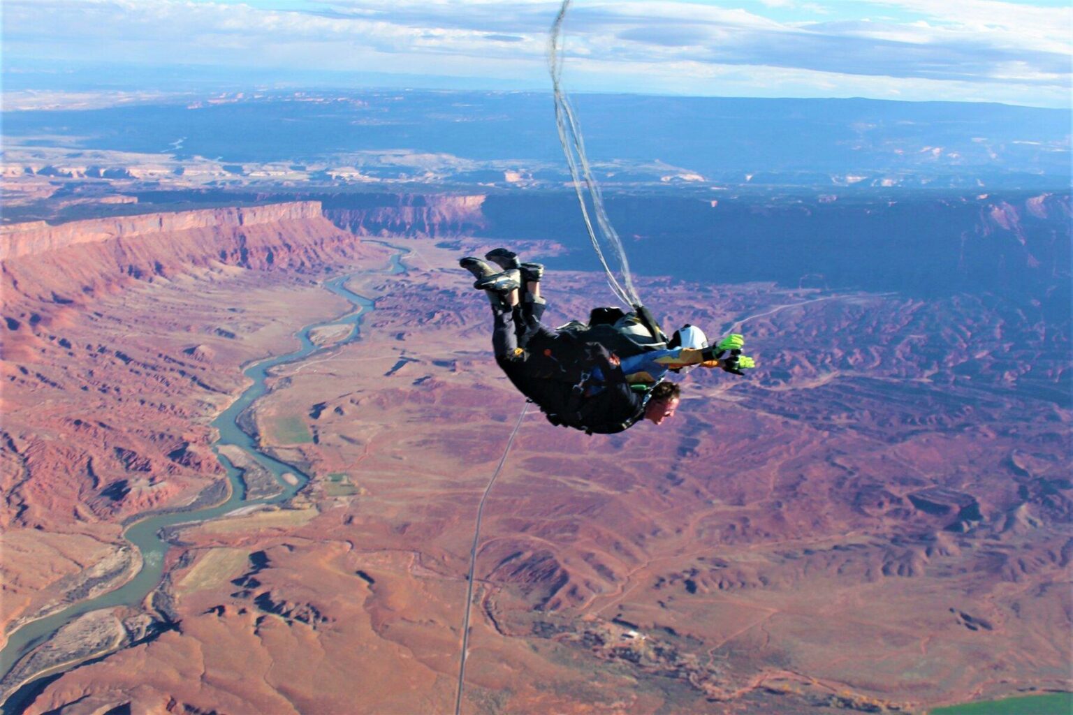 Guide and guest tied together as they skydive over Moab's red landscape