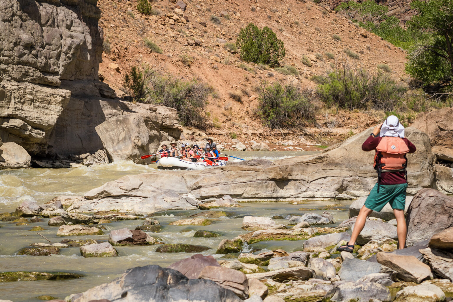 Desolation Canyon - Man tking photo of boat going through rapids