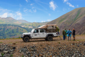 Jeep Gladiator parked ontop of a mountain with guests climbing into the back of the jeep - scenic mountains and blue sky - La PLata Canyon - Mild to Wild