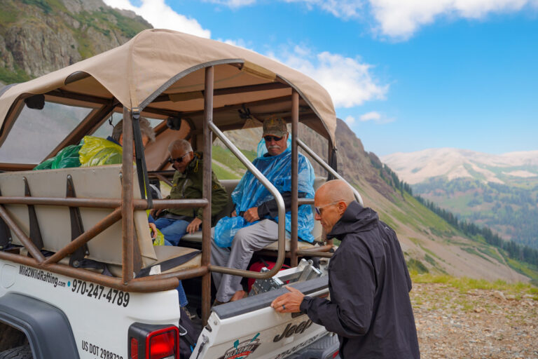 Guide shutting the tailgate of a Jeep Gladiator with guests sitting in the bed - Scenic background - La Plata Canyon - Mild to Wild