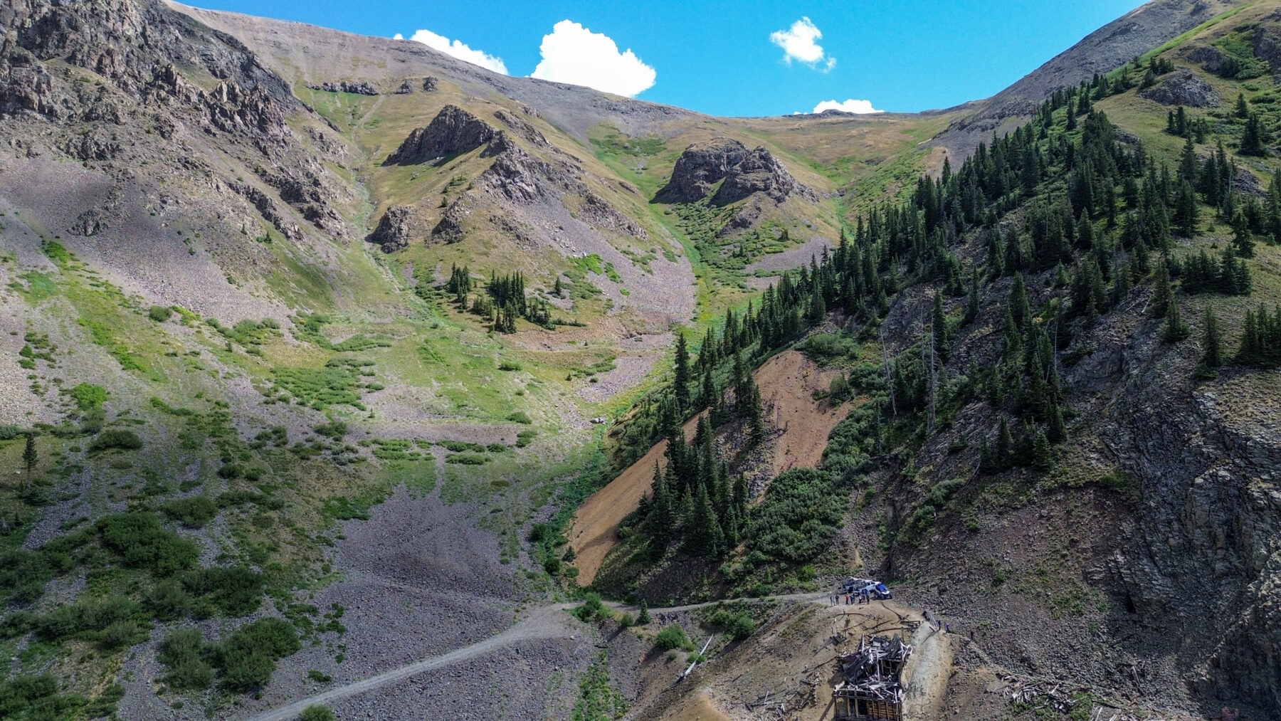 Aerial wide shot of a mine with mountains in background at the top of mini gulch in Silverton, CO - Mild to Wild