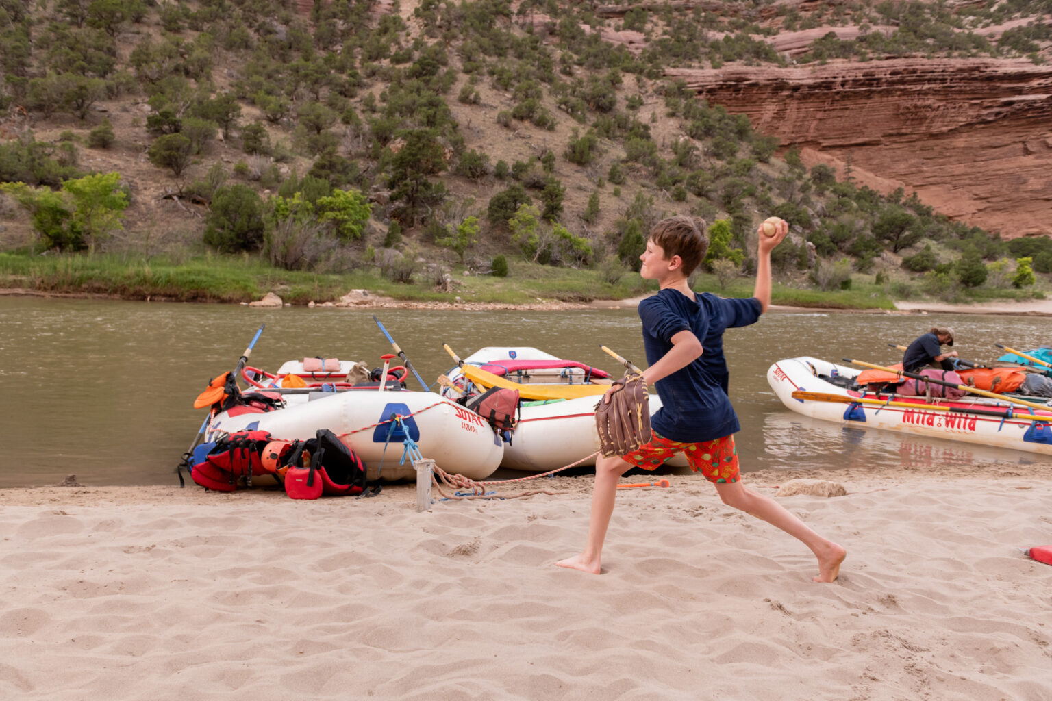 Side view of a kid throwing a baseball with rafts and the river in background - Gates of Lodore - Mild to Wild