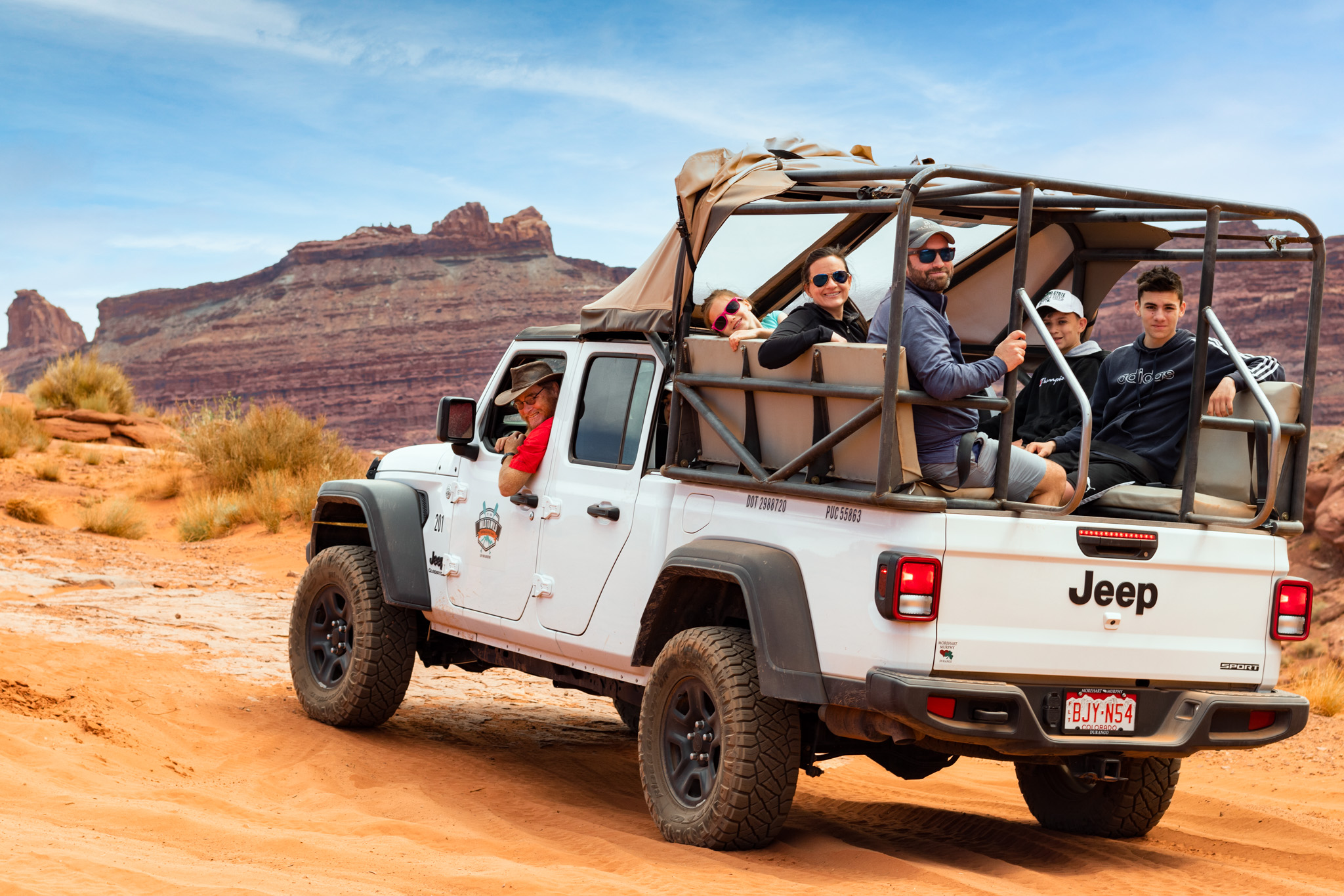 driver and Guests in jeep gladiator smiling at camera in moab desert - Mild to Wild