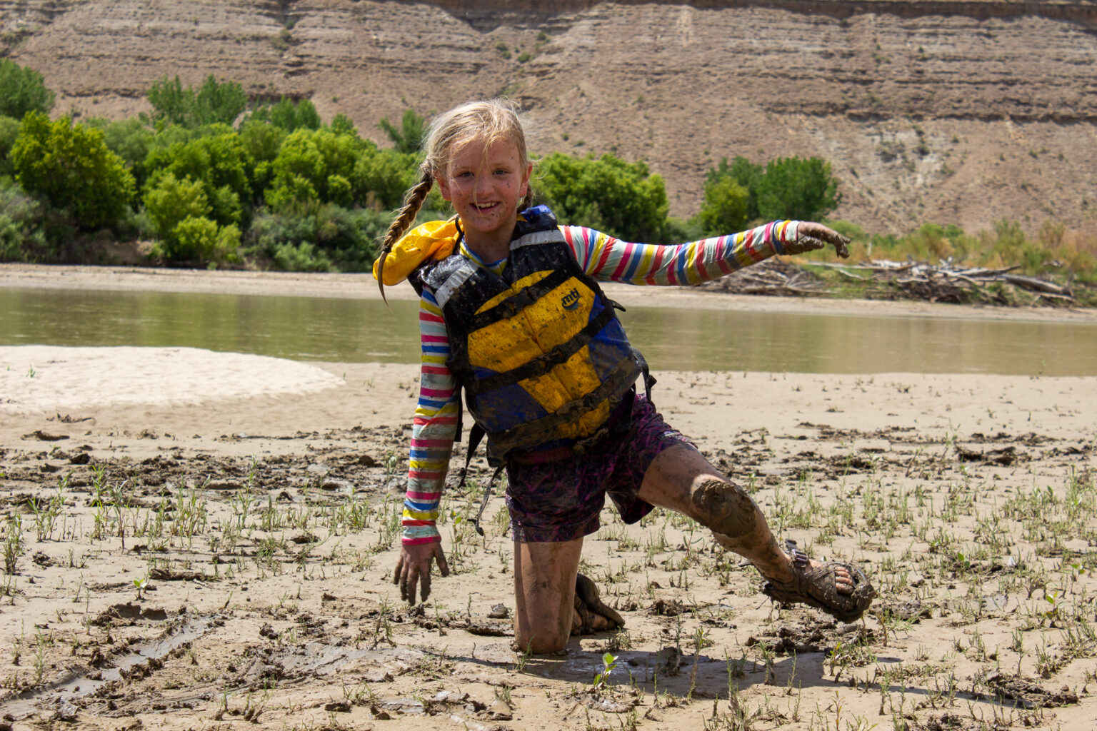 Girl playing in the mud on the beach in Desolation Canyon on a rafting trip - Mild to Wild