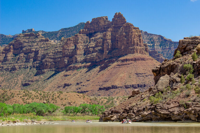 Big cliffs looms over a raft on the Green River in Desolation Canyon - Mild to Wild