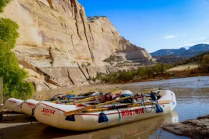 Three rafts beached at a camp next to a massive Weber sandstone cliff on the Yampa River - Mild to Wild