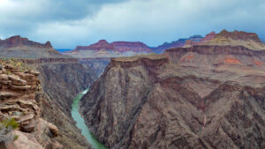 Plateau Point is 1.5 miles ( 2.4 km ) beyond Indian Garden. This is a strenuous day hike that takes 8-12 hours round trip (on Bright Angel Trail) from Grand Canyon Village. The total round trip distance is 12.2 miles (19.6 km ). The change in elevation is 3,195 feet (974 m). This hike should not be attempted during the summer months, when inner canyon temperatures reach over 100 F (38 C). The Colorado River, over 1000 feet below the spot where this photo was taken, has cut through this hard schist rock and preceded the work of other erosive forces. The result is the "Inner Gorge," a canyon within a canyon. Description: a green river flowing at the bottom of a rocky gorge with steep stone walls. In the distance colorful cliffs. NPS/M.Quinn