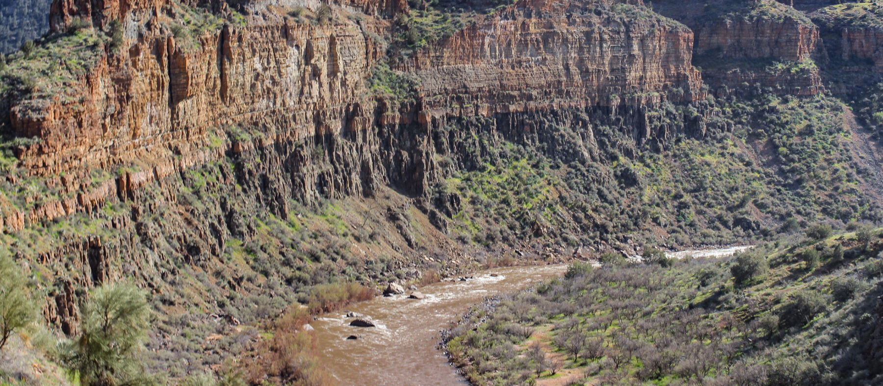 Grand view of a bend along the Upper Salt River Canyon with huge vertical cliffs looming above the river