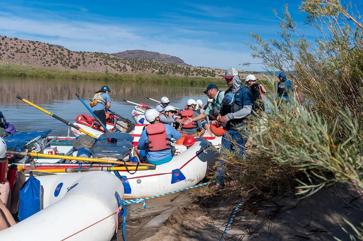 A rafting group loading boats on the edge of the river