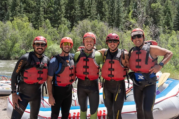A group of rafters pose in their wet suits and life jackets